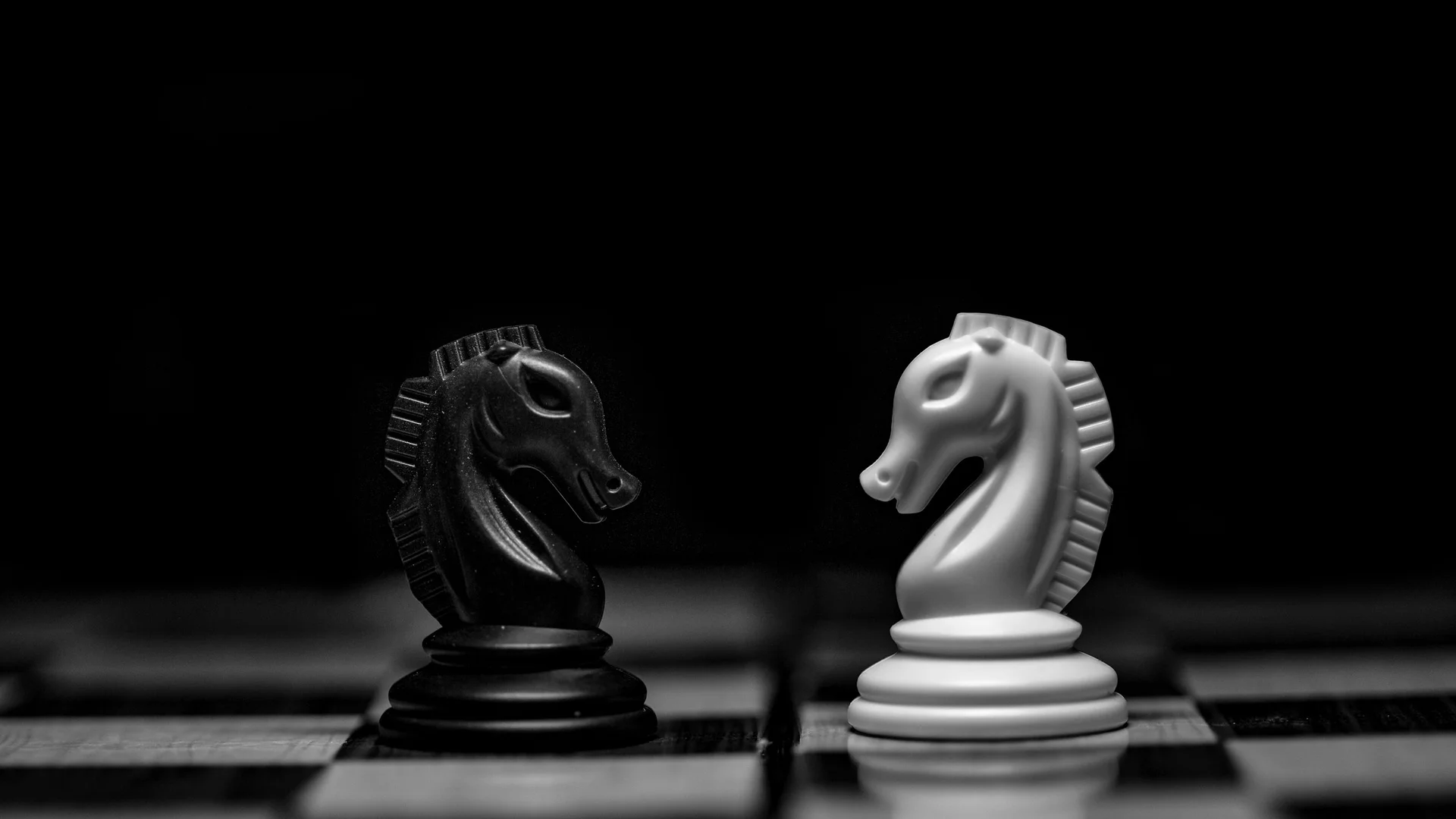 Dois cavalos de xadrez frente a frente representando a decisão entre terceirizar a TI ou montar equipe interna